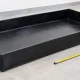 Bandeja antiderrame HDPE rectangular negra junto a una cinta métrica